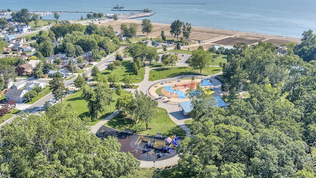 Luchtbeeld van een kustplaats met een park, strand en jachthaven.