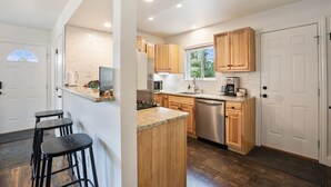 A modern kitchen with wooden cabinets, a stainless steel dishwasher, and a granite countertop. - NEW Updated, SUNSETCABIN:3 bd,1.5 bth, secluded, beautiful views, deck, sleeps 6 (Florissant)