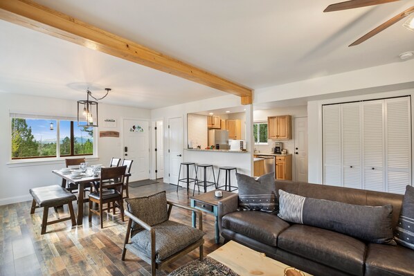 A spacious living area with a dining table, sofa, and kitchen in the background.