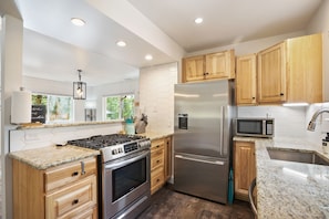 A modern kitchen with wooden cabinets, stainless steel appliances, and a granite countertop.