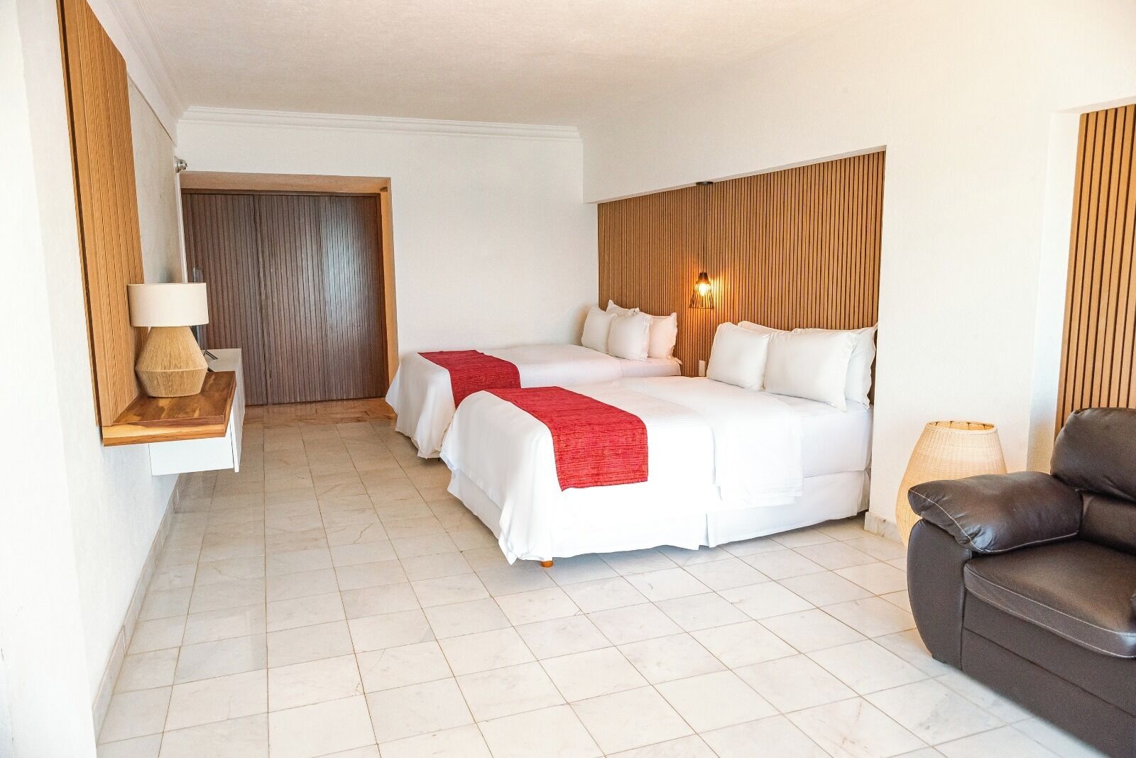 A hotel room with a bed, a chair, and a lamp.