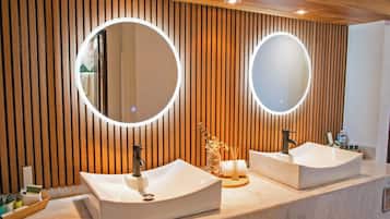 Un baño moderno con dos lavamanos, paneles de madera y espejos redondos.