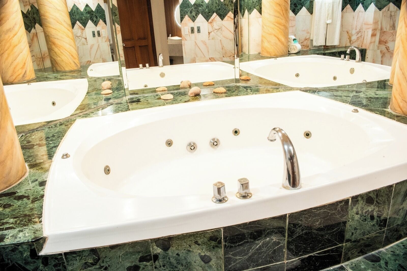 A large, oval-shaped bathtub with a single faucet, surrounded by a marble countertop.