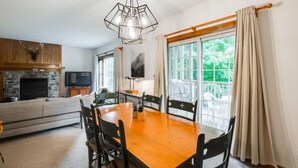 A dining area with a wooden table and chairs, a television, and a fireplace. - On the mountain, Ski-in/out in nature (Mont-Tremblant)