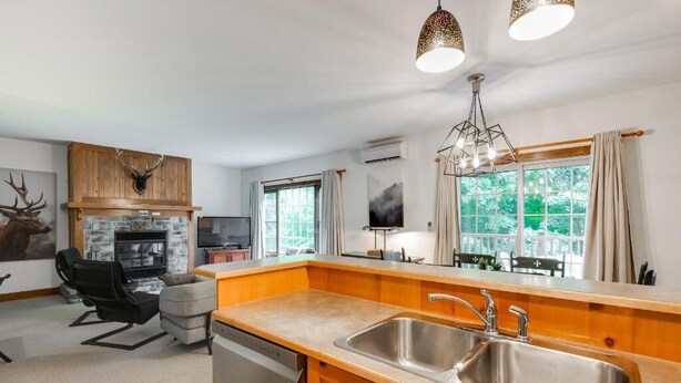 A modern kitchen with a wooden countertop, stainless steel sink, and a built-in oven. - On the mountain, Ski-in/out in nature (Mont-Tremblant)