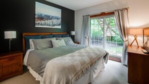 A bedroom with a large bed, a nightstand, a desk, and a window with curtains. - On the mountain, Ski-in/out in nature (Mont-Tremblant)