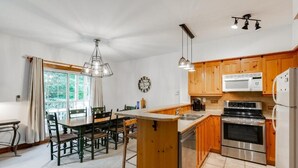 A kitchen with wooden cabinets, a stainless steel stove, a microwave, and a refrigerator. - On the mountain, Ski-in/out in nature (Mont-Tremblant)