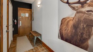 A hallway with a wooden door, a bench, a rug, and a wall-mounted light fixture. - On the mountain, Ski-in/out in nature (Mont-Tremblant)
