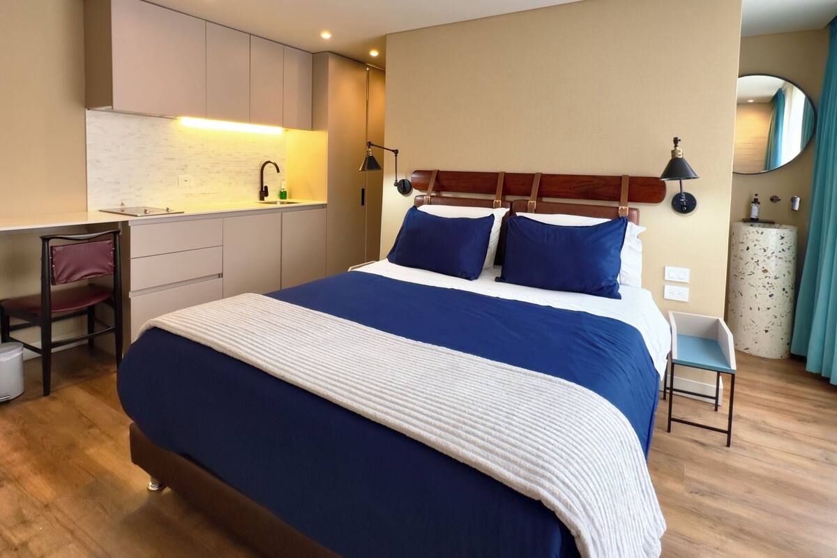 Una habitación de hotel moderna con una cama grande, un escritorio y una kitchenette.