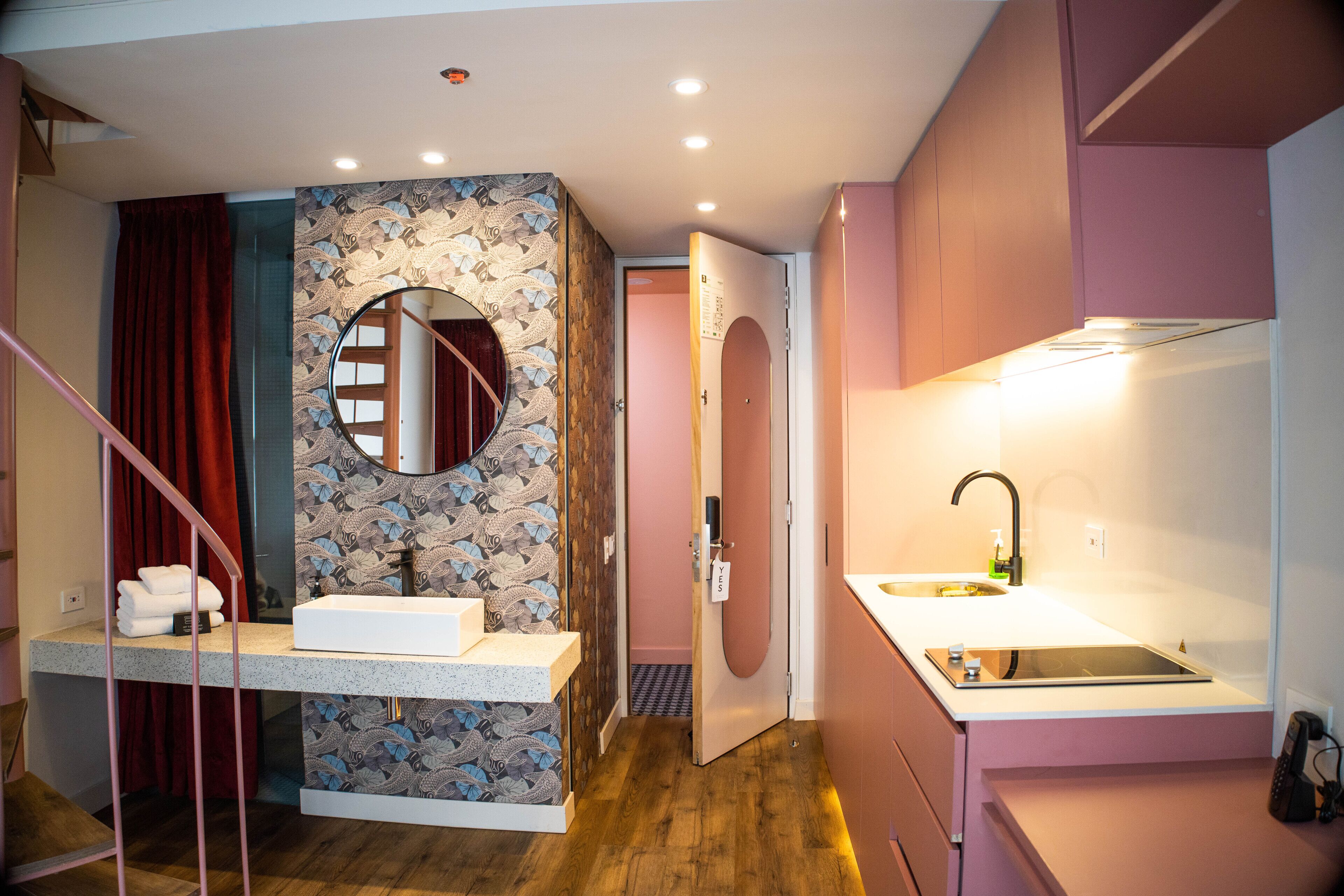 A modern bathroom with a vanity, a round mirror, and a shower area.