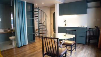 A modern kitchen with a dining area, a staircase, and a bathroom.