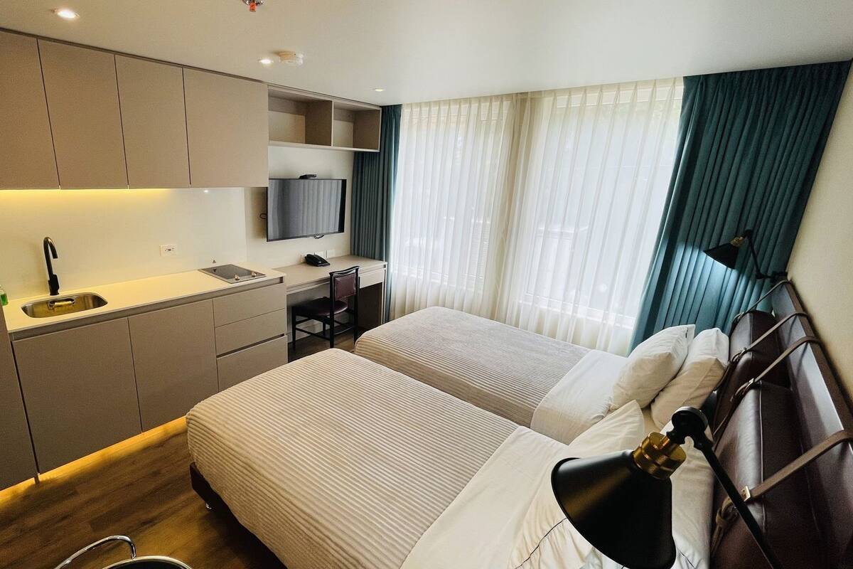 Una habitación de hotel con dos camas, un escritorio con una silla, un televisor y un lavamanos.