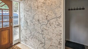 A room with a large map on the wall, a wooden door, and a coat rack with hooks. - A nature lovers delight. (Ludham)