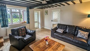 A living room with a black leather sofa, a wooden coffee table, and a black leather couch. - A nature lovers delight. (Ludham)