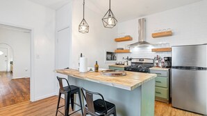 Een moderne keuken met een centraal kookeiland, roestvrijstalen apparatuur en hangende吊り下げライト.