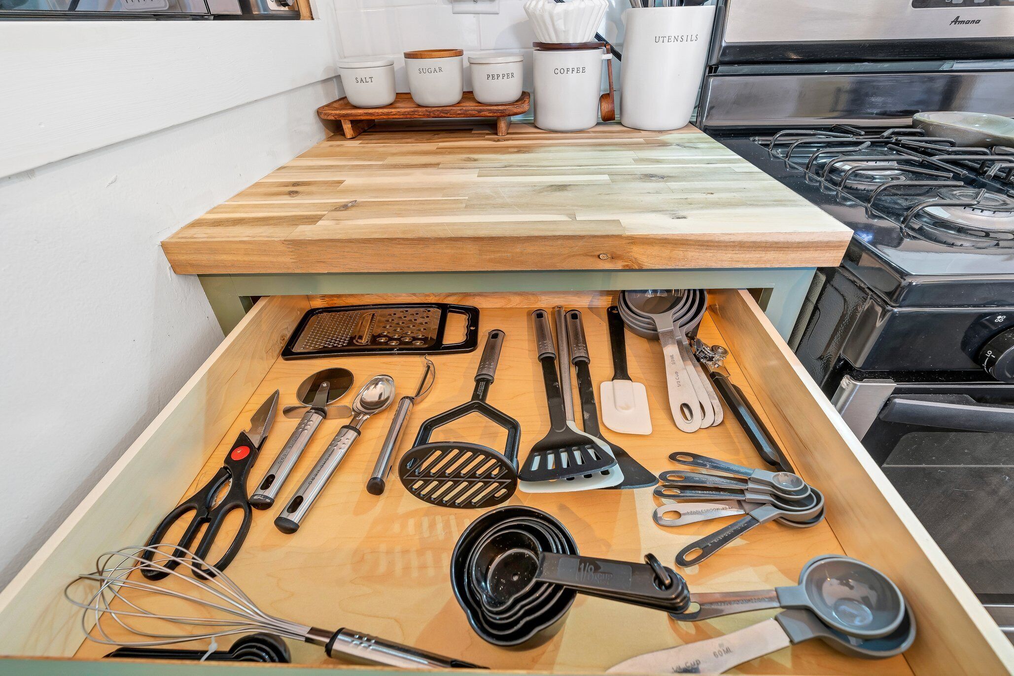 A kitchen drawer with various utensils and kitchenware.