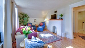 A living room with a fireplace, a television, and a large plant.