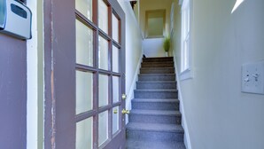 A staircase leading to a landing with a door and a light switch on the wall.