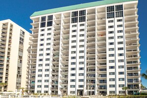 A high-rise hotel with multiple balconies, a green roof, and a modern architectural design.