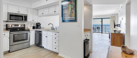 A modern kitchen with white cabinets, stainless steel appliances, and a wooden dining table.