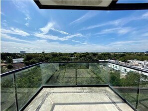 Enjoy the expansive view from this balcony with a glass railing and tiled floor.