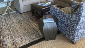 Ein Wohnzimmer mit Ecksofa, gestreiftem Ottomanen, Couchtisch und einer Treppe mit Holzwertungen.