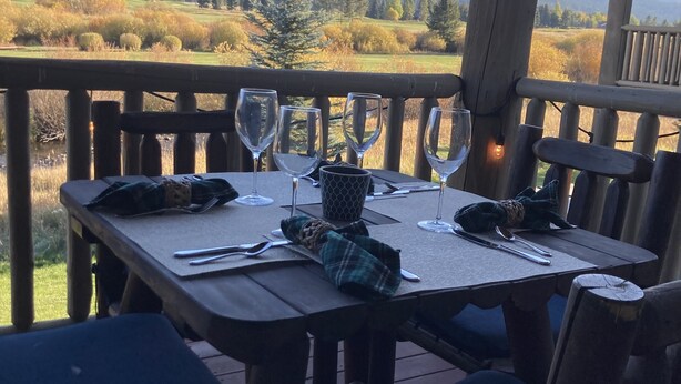 Eine Holzterrasse mit einem Tisch für zwei Personen, mit Blick auf eine malerische Landschaft.