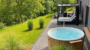 Een bubbelbad in een tuin met terras en buitenmeubilair.