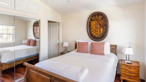 A bedroom with a large bed, a mirror, a wooden nightstand, and a wall-mounted artwork. - Steps to La Jolla Cove with Gorgeous Views, Village Living at its Finest! (San Diego)