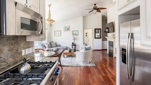A spacious kitchen with modern appliances, a dining area with a glass table, and a cozy seating area with a fireplace. - Steps to La Jolla Cove with Gorgeous Views, Village Living at its Finest! (San Diego)