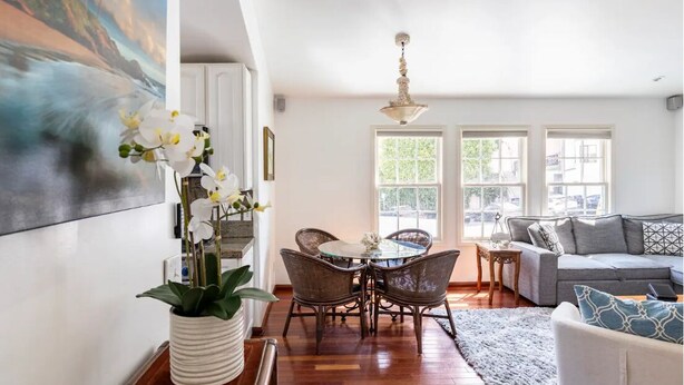 A spacious living room with a dining area, large windows, and a modern chandelier. - Steps to La Jolla Cove with Gorgeous Views, Village Living at its Finest! (San Diego)