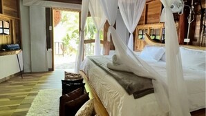 Una habitación con una cama bajo un dosel, muebles de madera y vistas al exterior.