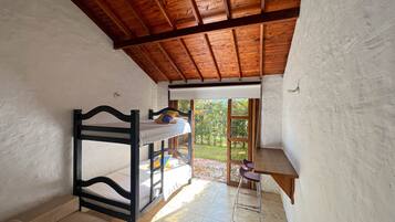 Dormitorio con literas, techo de madera, una mesita y vistas a la vegetación.
