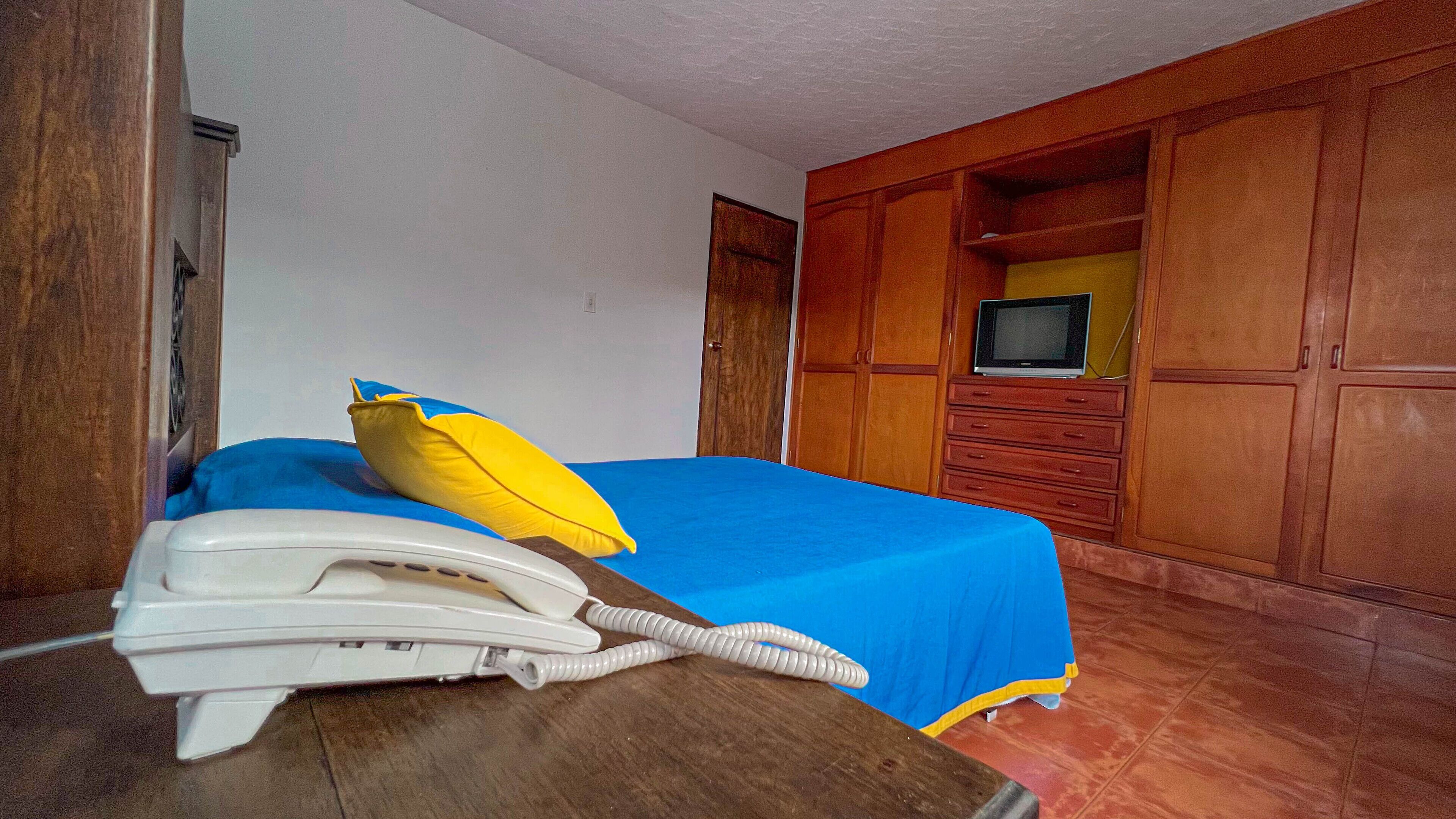 Una habitación de hotel con una cama, un teléfono y armarios de madera.