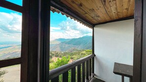 Een balkon met houten spijlen, met uitzicht op een bergachtig landschap.