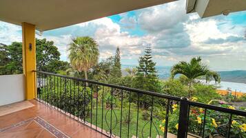 Un balcón con vistas a un jardín exuberante y un paisaje lejano.