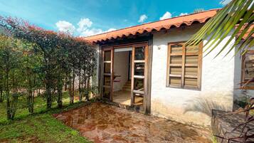 A house with a tiled roof, a stone patio, and a door leading to an interior space.
