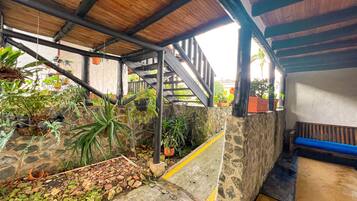 A covered outdoor area with stone walls, potted plants, and a wooden bench.