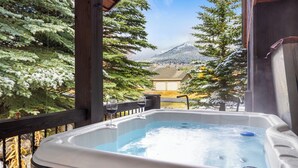 Banyera d'hidromassatge amb vista a arbres i muntanyes cobertes de neu.
