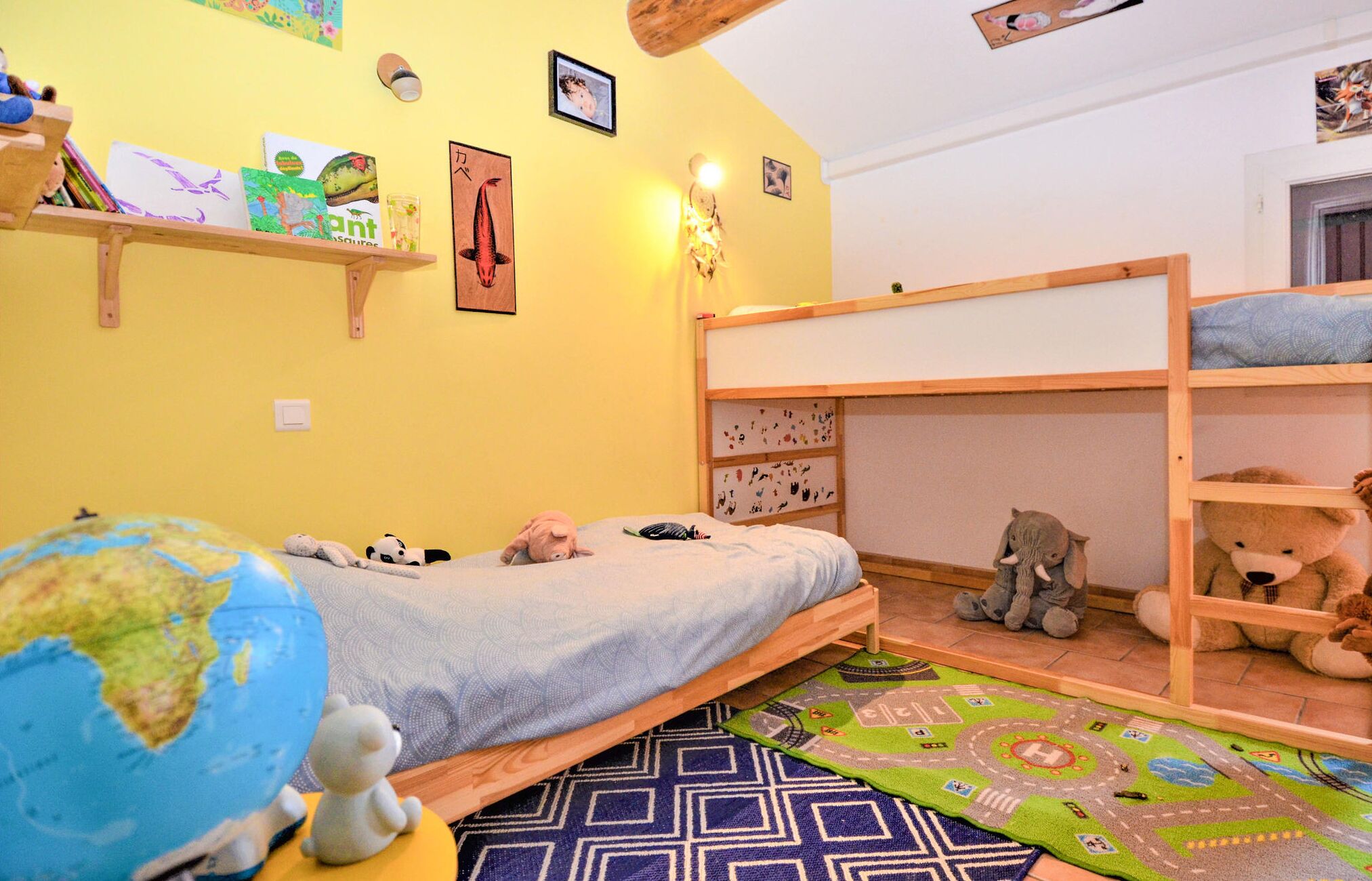 A child's bedroom with a bunk bed, a globe, stuffed animals, and educational posters on the walls.