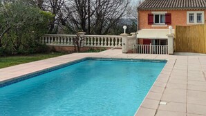 Una piscina rectangular con borde de azulejos, rodeada por una terraza también de azulejos.