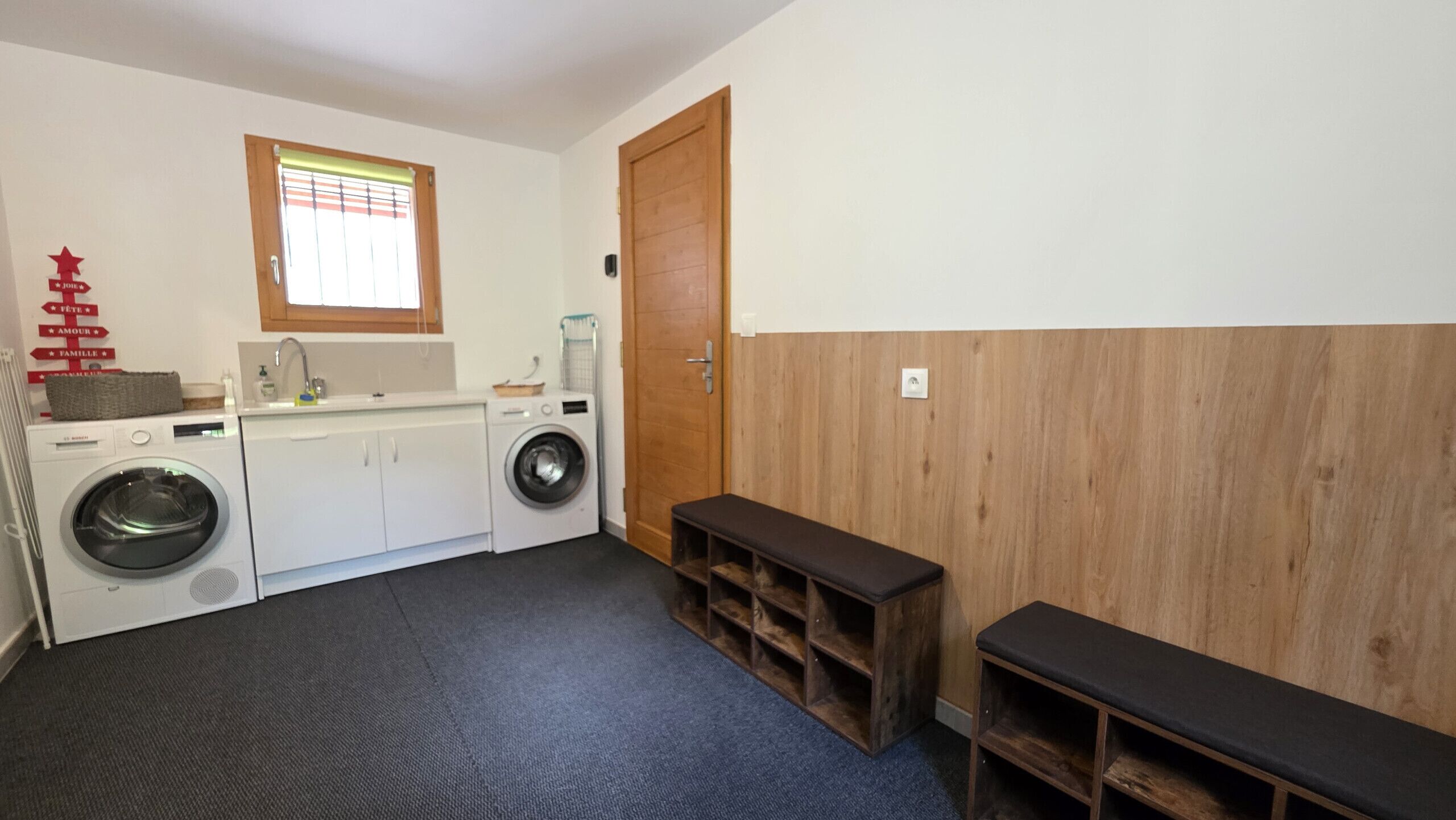 Una sala de lavandería con lavadora, secadora y un banco.
