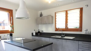 Eine moderne Küche mit einer zentralen Kochinsel, einer eingebauten Spüle und einem Fenster mit Jalousien.
