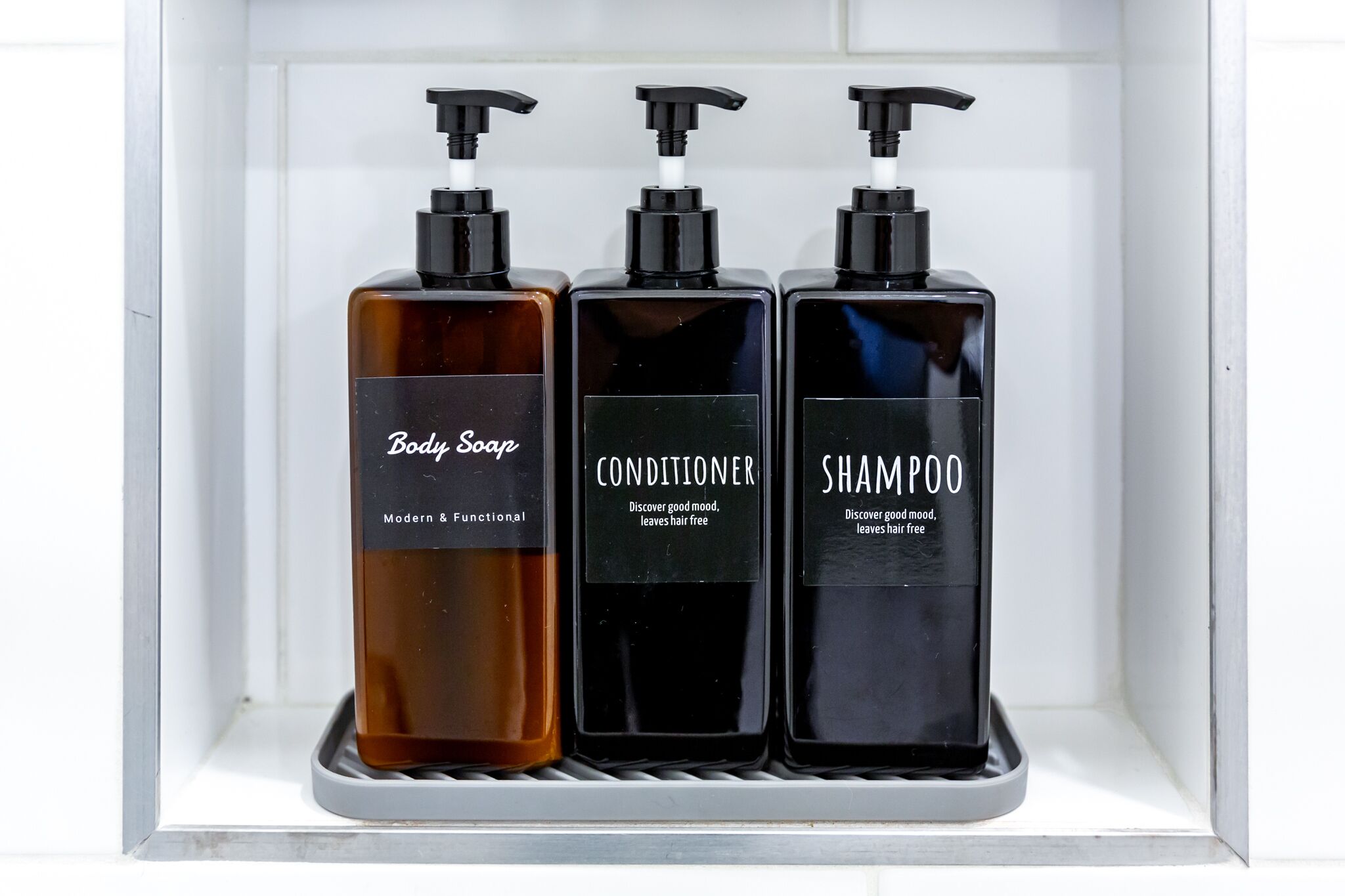 Three bottles of body care products in a white shelf.