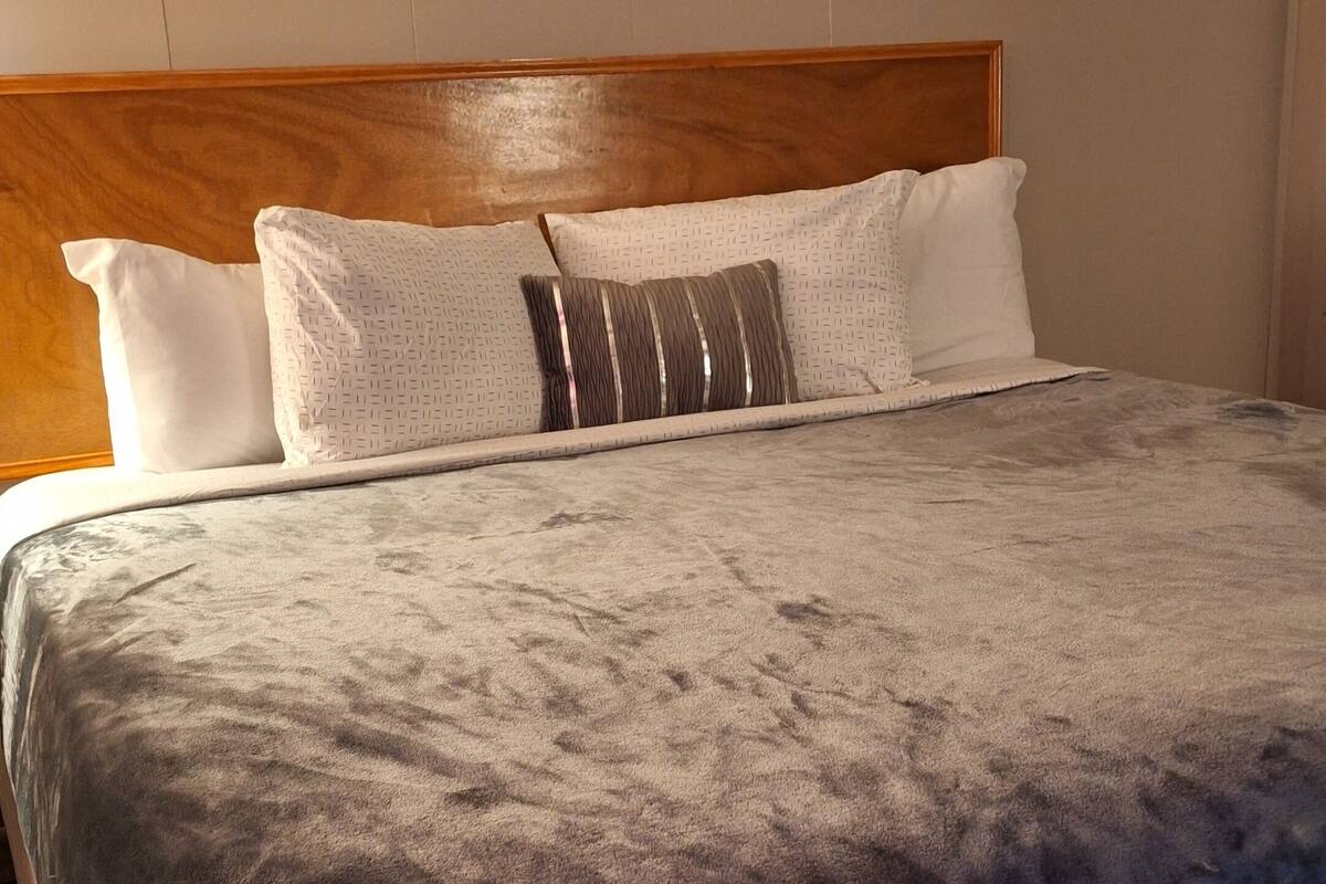 A neatly made bed with a patterned bedspread, a wooden headboard, and several pillows.