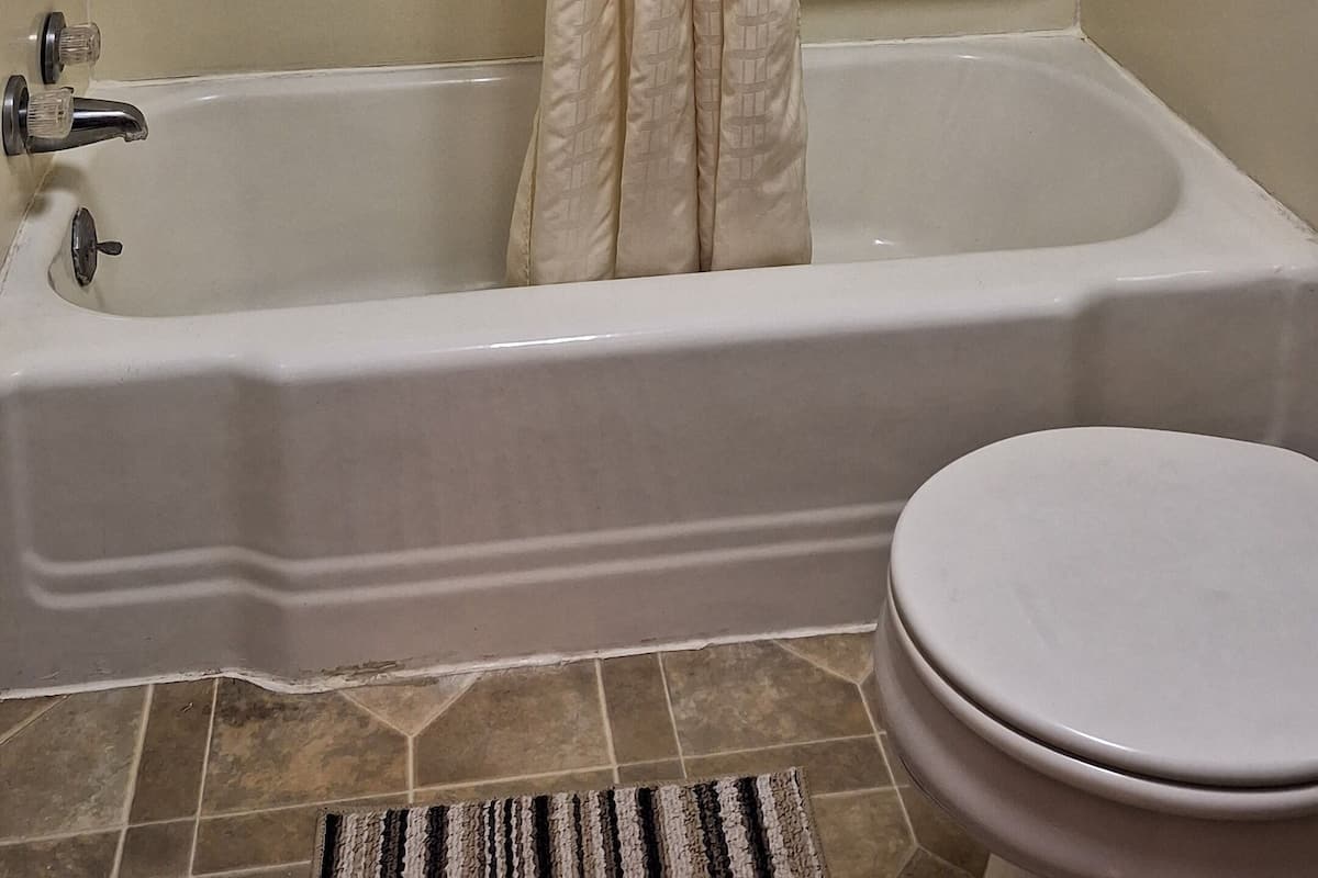A bathroom with a bathtub, toilet, and shower curtain.