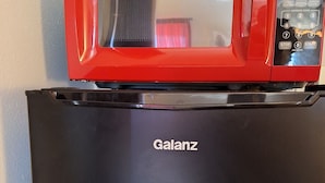 A black Galanz refrigerator with a red microwave on top. - Comanche inn (Coldwater)