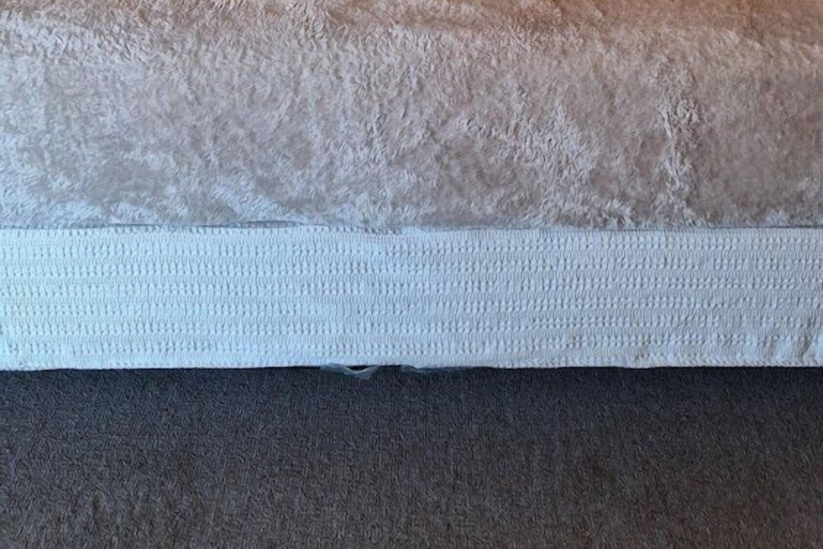 Una cama con cabecera de madera, un edredón texturizado y dos almohadas.