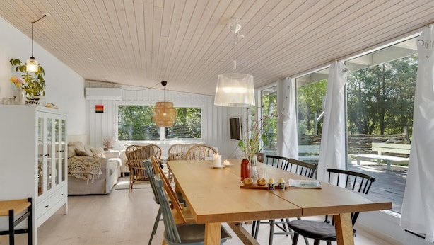 A spacious dining area with a wooden table and chairs, large windows offering a view of the outdoors, and a cozy seating area with a sofa and chairs. - Gorgeous home in Højby with WiFi (Højby)