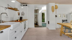 A modern kitchen with white cabinetry, a wooden countertop, and pendant lighting. There is a dining area with a wooden table and chairs. - Gorgeous home in Højby with WiFi (Højby)